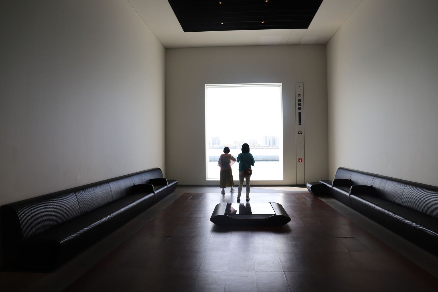 Modern museum gallery interior in Naples with warm late-afternoon light through tall glass