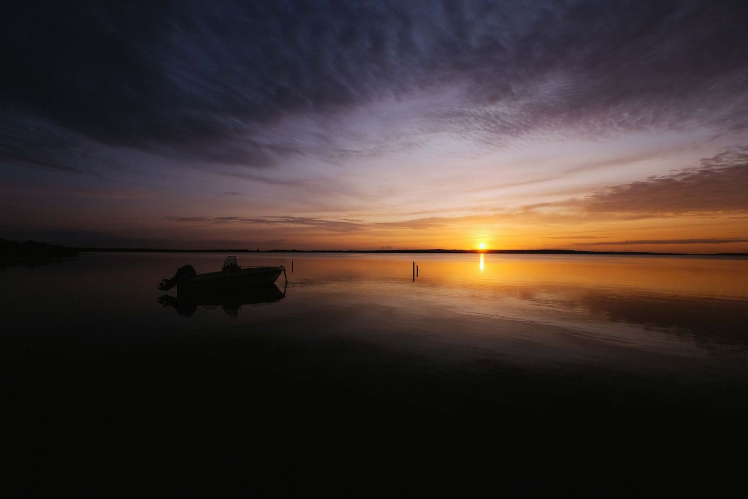 Glassy sunrise water off Naples with a single small boat wake