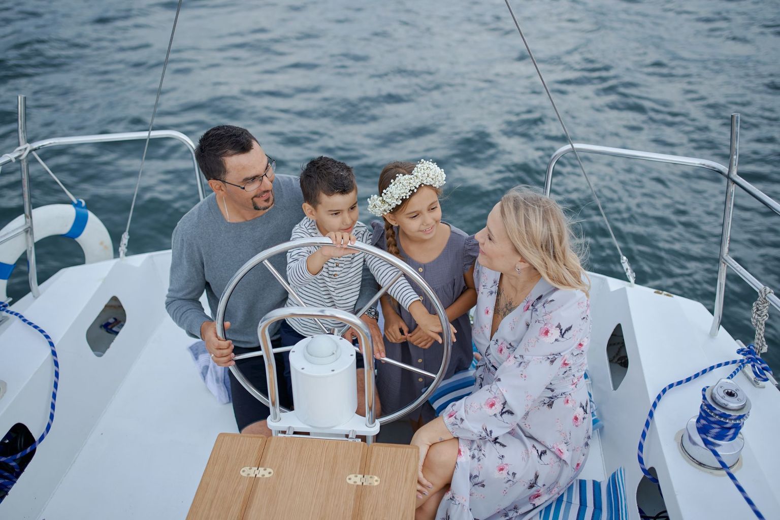Family in life jackets on the bow of a small boat watching dolphins in turquoise Gulf water