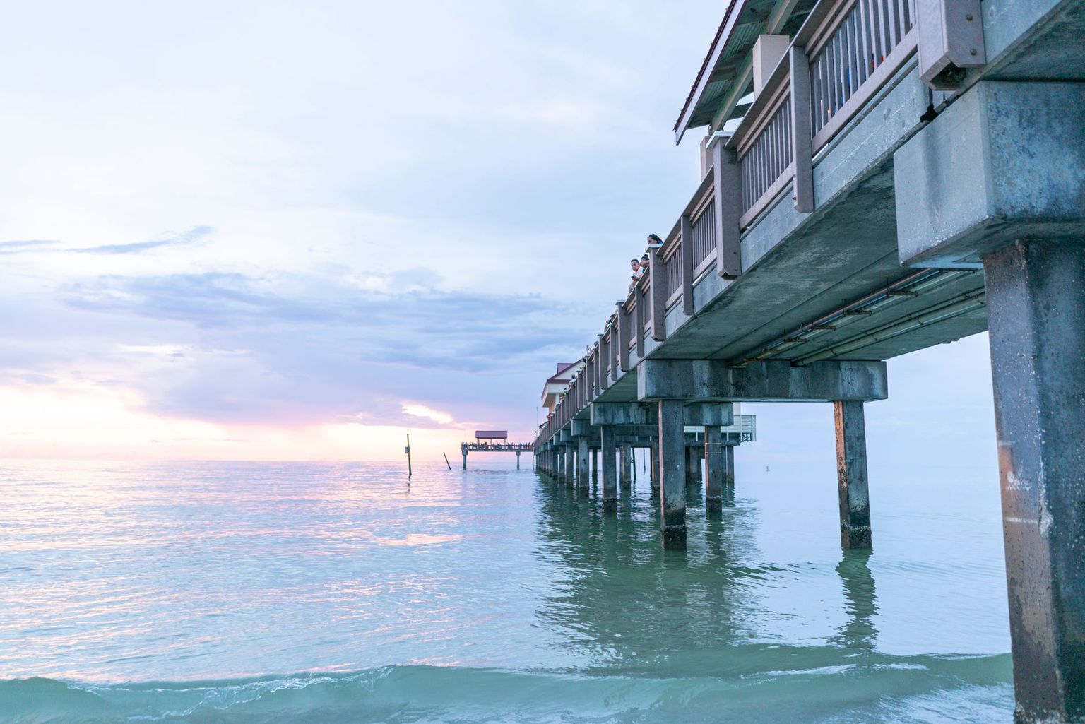The Naples Pier stretching into the Gulf of Mexico with people fishing at the rail